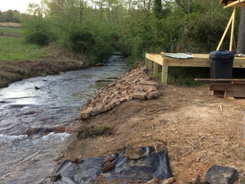 Stacking river rock along the creek bank to prevent soil erosion and dress up the view.